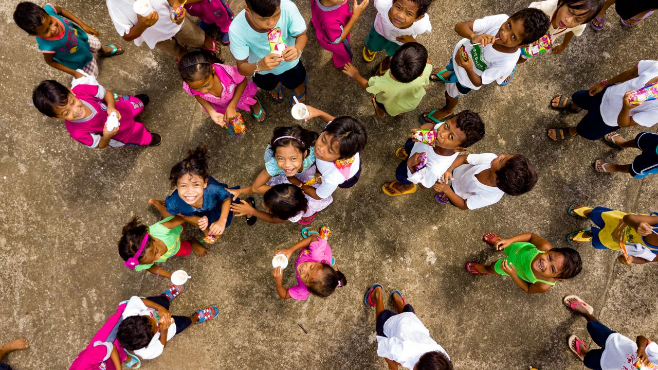 A vibrant top view of cheerful children gathered on pavement, smiling and socializing.